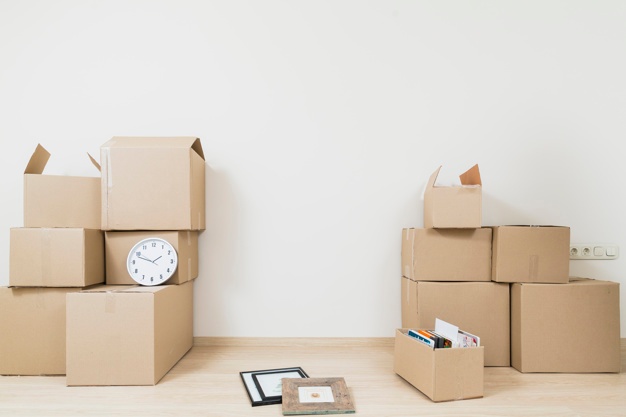 stacked moving cardboard boxes with clock picture frame against white wall 23 2148060008