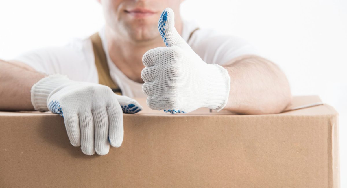 Professional help with relocation. Thumb up of worker with gloves on white background.